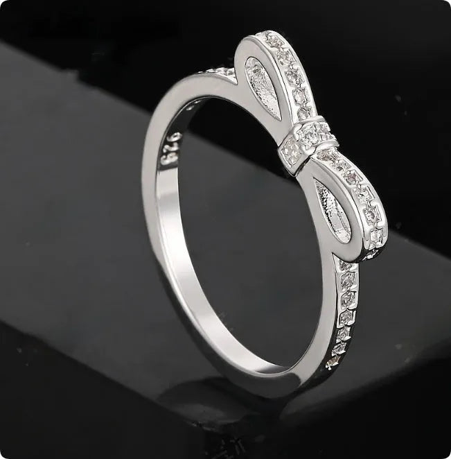 Silver bow-shaped ring with rhinestone zircon crystal detailing showing side profile view