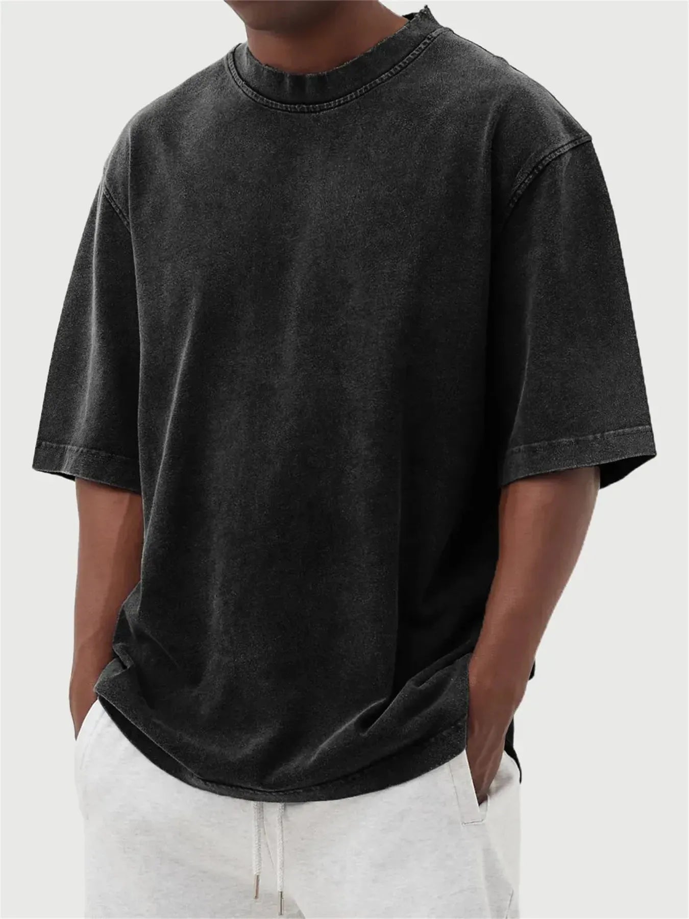 Man wearing a loose-fit, stone-washed distressed pullover T-shirt in a solid colour.