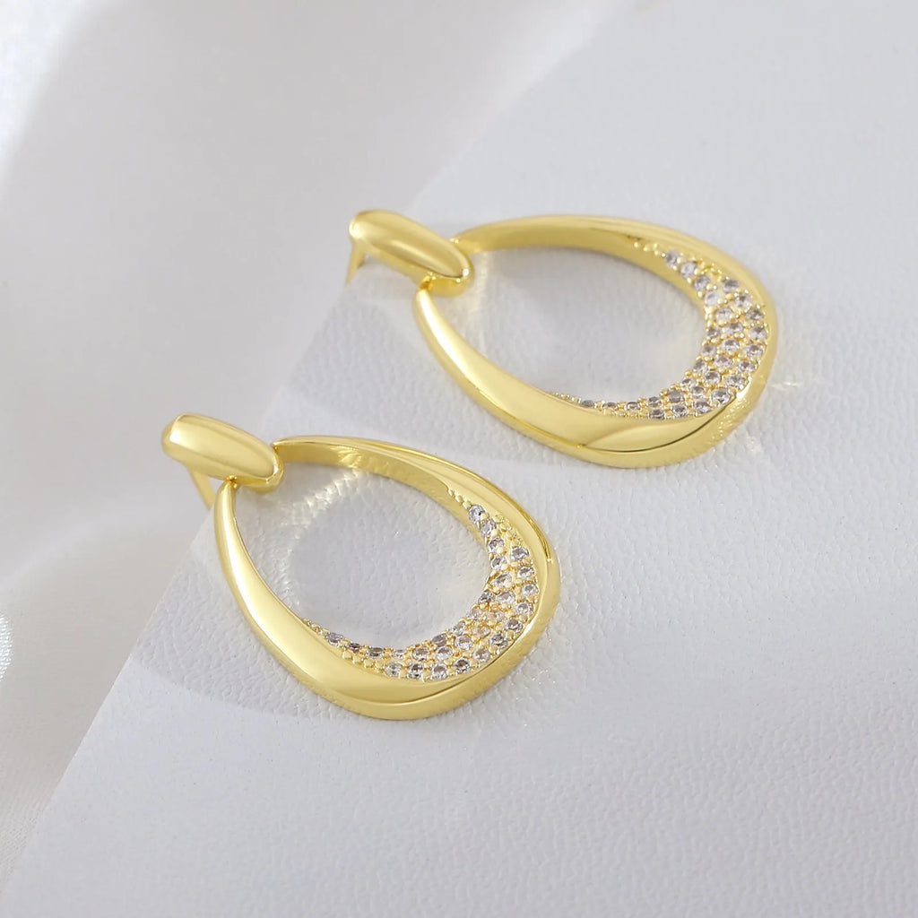 Yellow gold geometric drop earrings with oval and round ring elements on copper