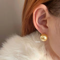 A pair of large silver pearl stud earrings with an eight-pointed star geometric design on a white background.