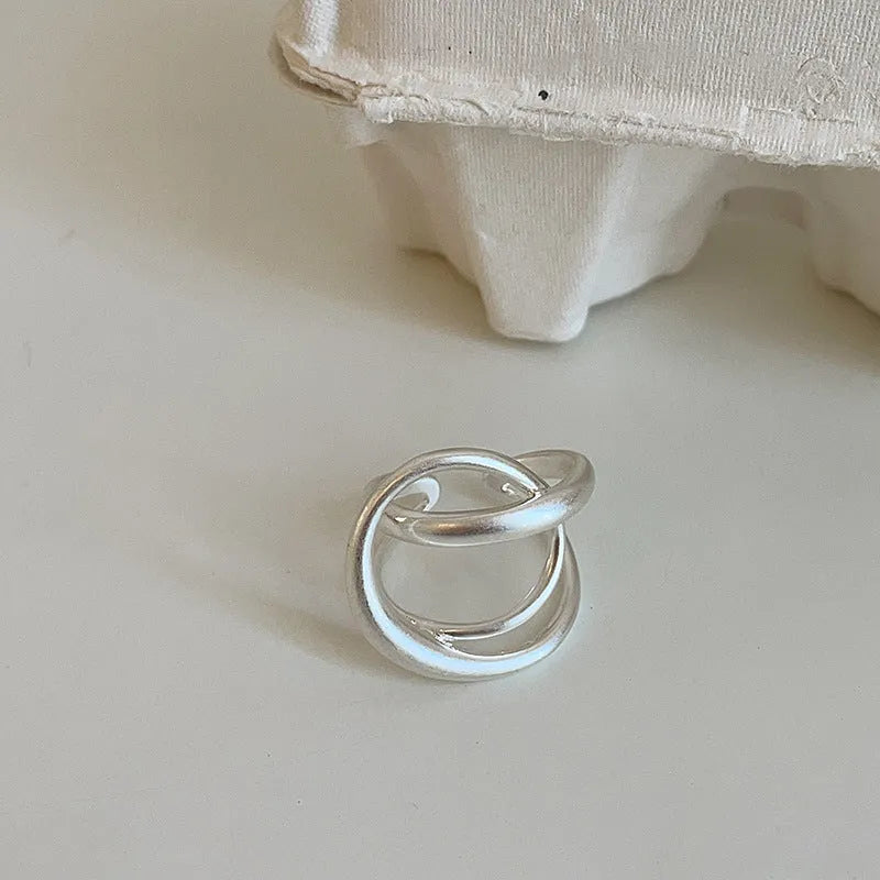 Geometric interlaced open ring with a matte metal finish in gold tone plating.
