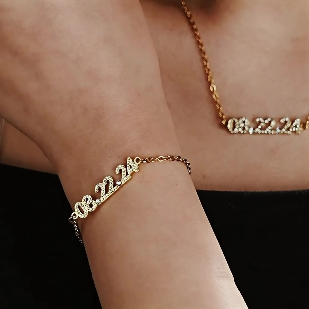 Stainless steel digital bracelet or necklace with diamond-set numbers on display, shown in gold colour.