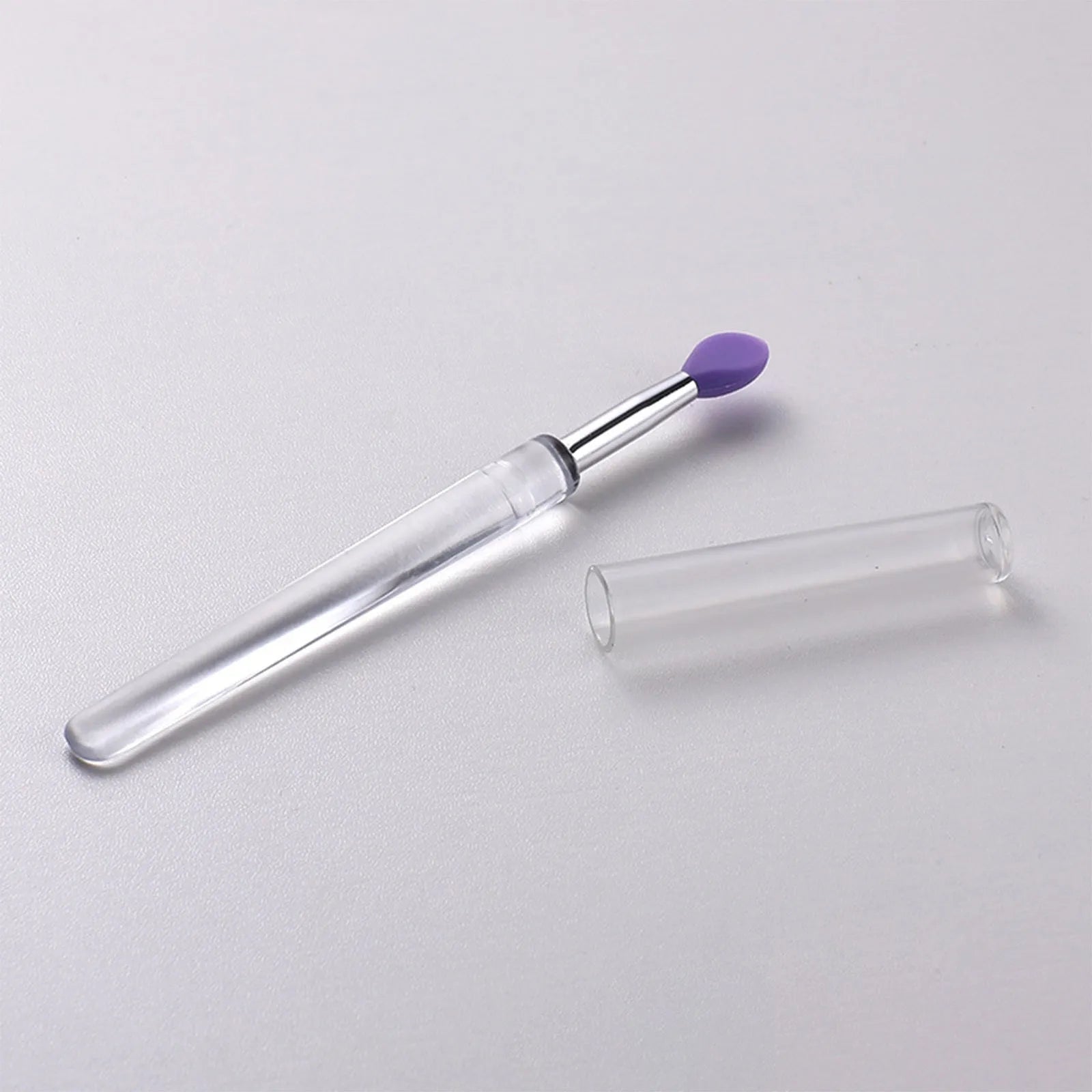 Set of eight colourful reusable silicone lip brushes with hygienic protective caps laid out.