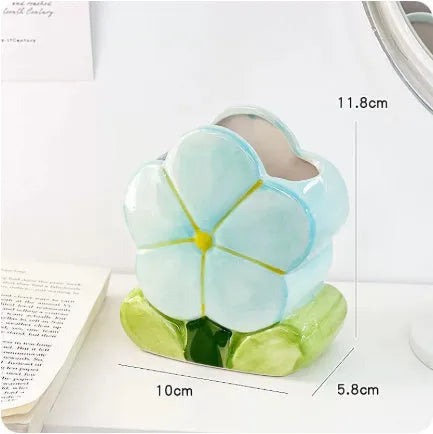 Ceramic pen holder box with floral pattern and lid on a wooden desk.