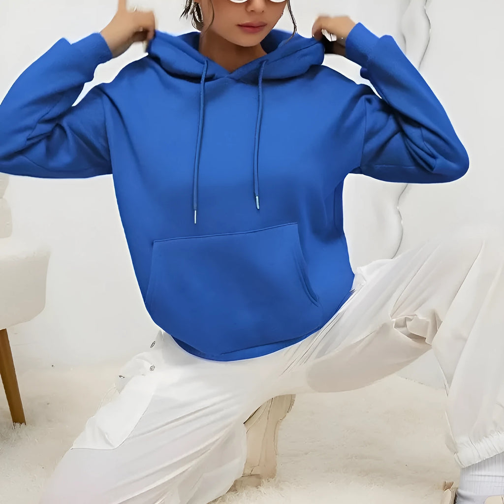 Woman wearing a loose grey drawstring waist sweatshirt with front pockets and long sleeves.