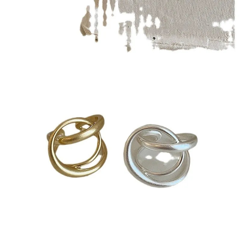Geometric interlaced open ring with a matte metal finish in gold tone plating.