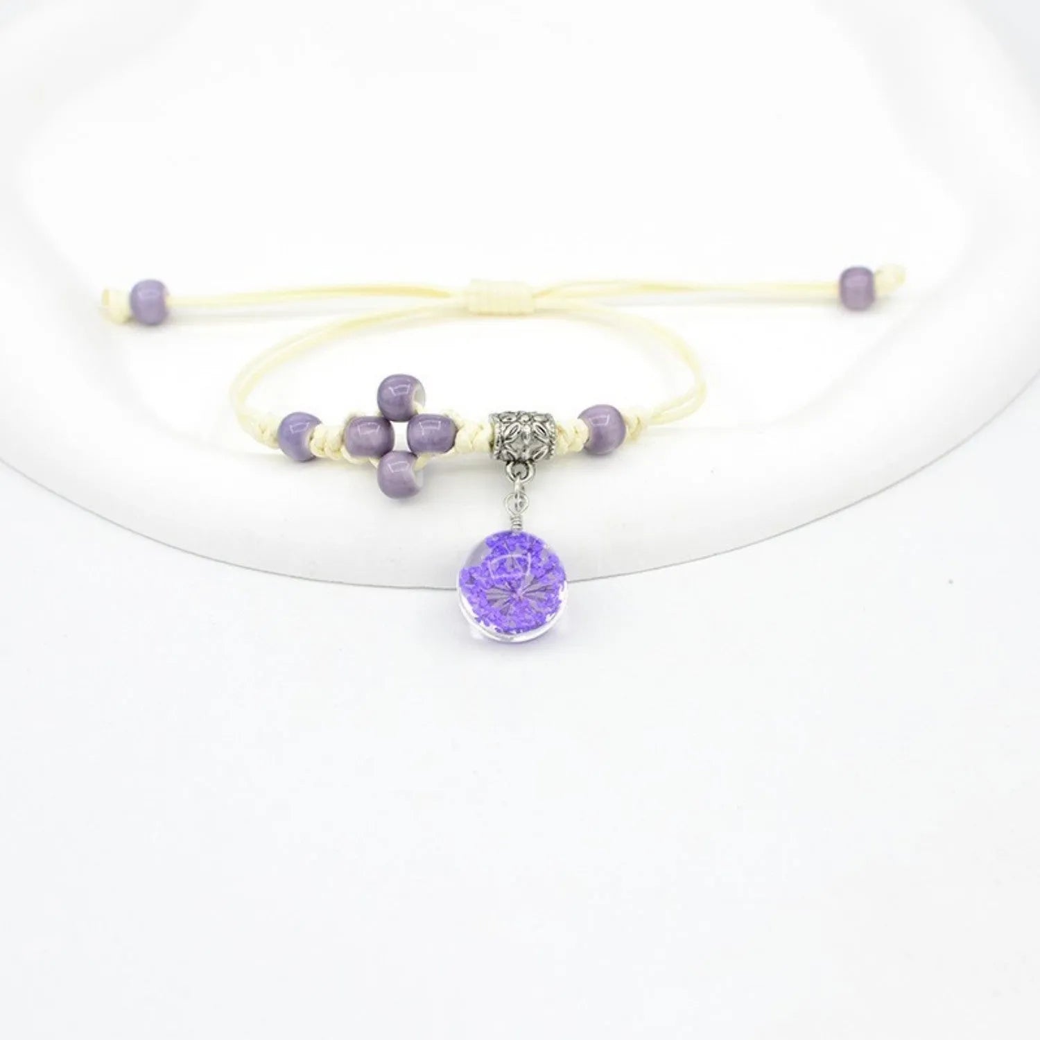 Glass bracelet with large colourful beads containing real dried flowers, on a white background.