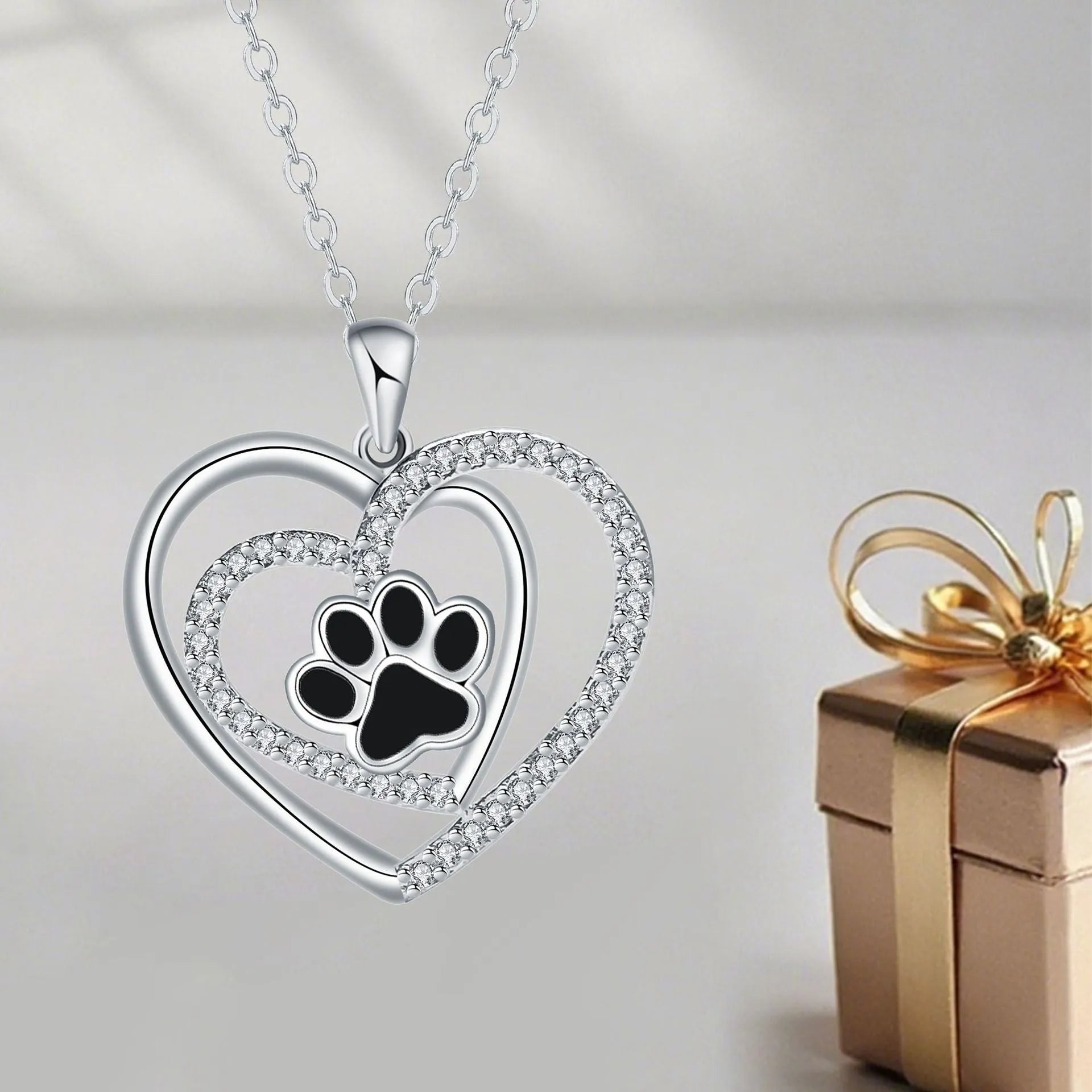 Women's dog paw print necklace with heart-shaped pendant on a cross chain.