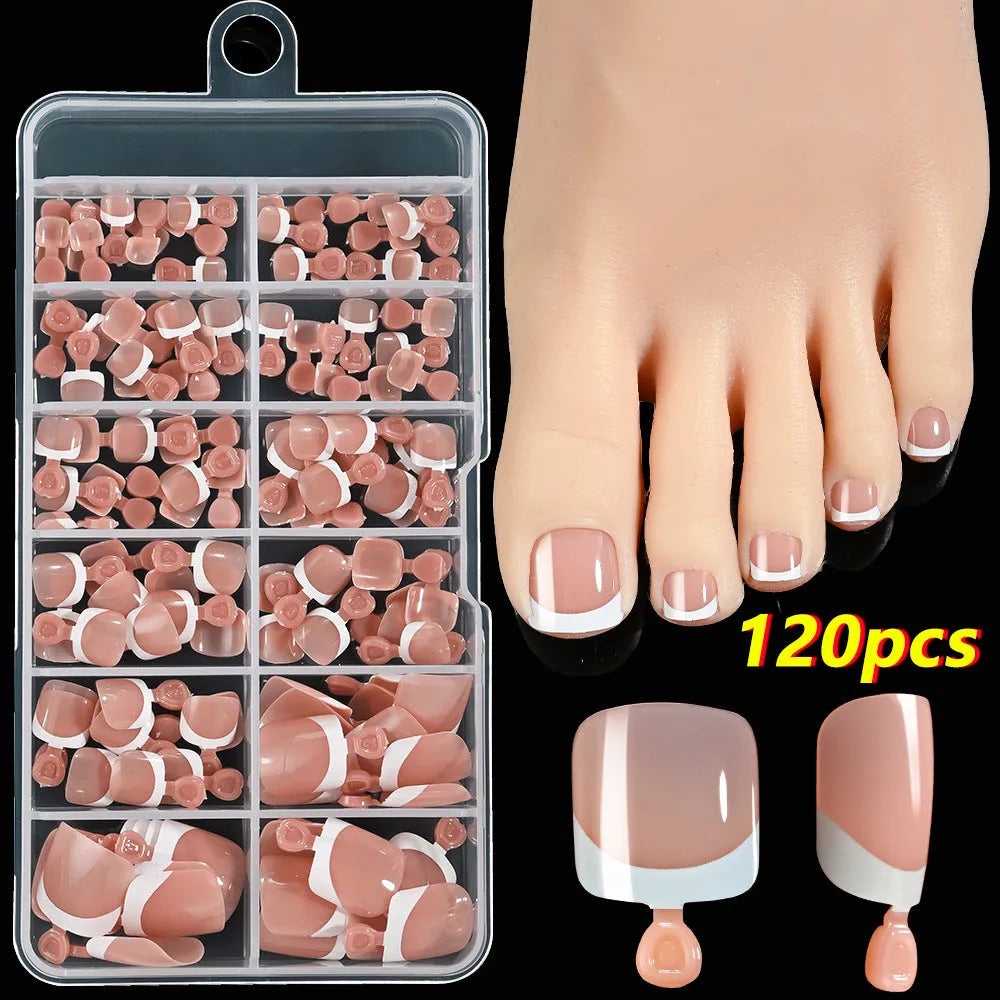 Box of 120 French white edge nude false toe nail pieces in assorted shades on a table