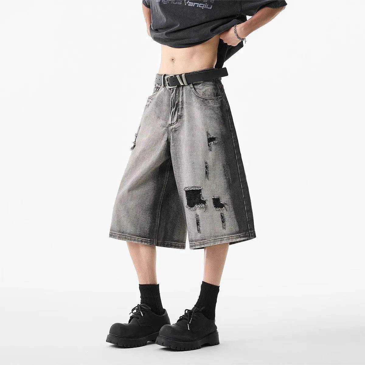 Gray distressed denim shorts with hole detailing, loose cropped fit on a plain background.