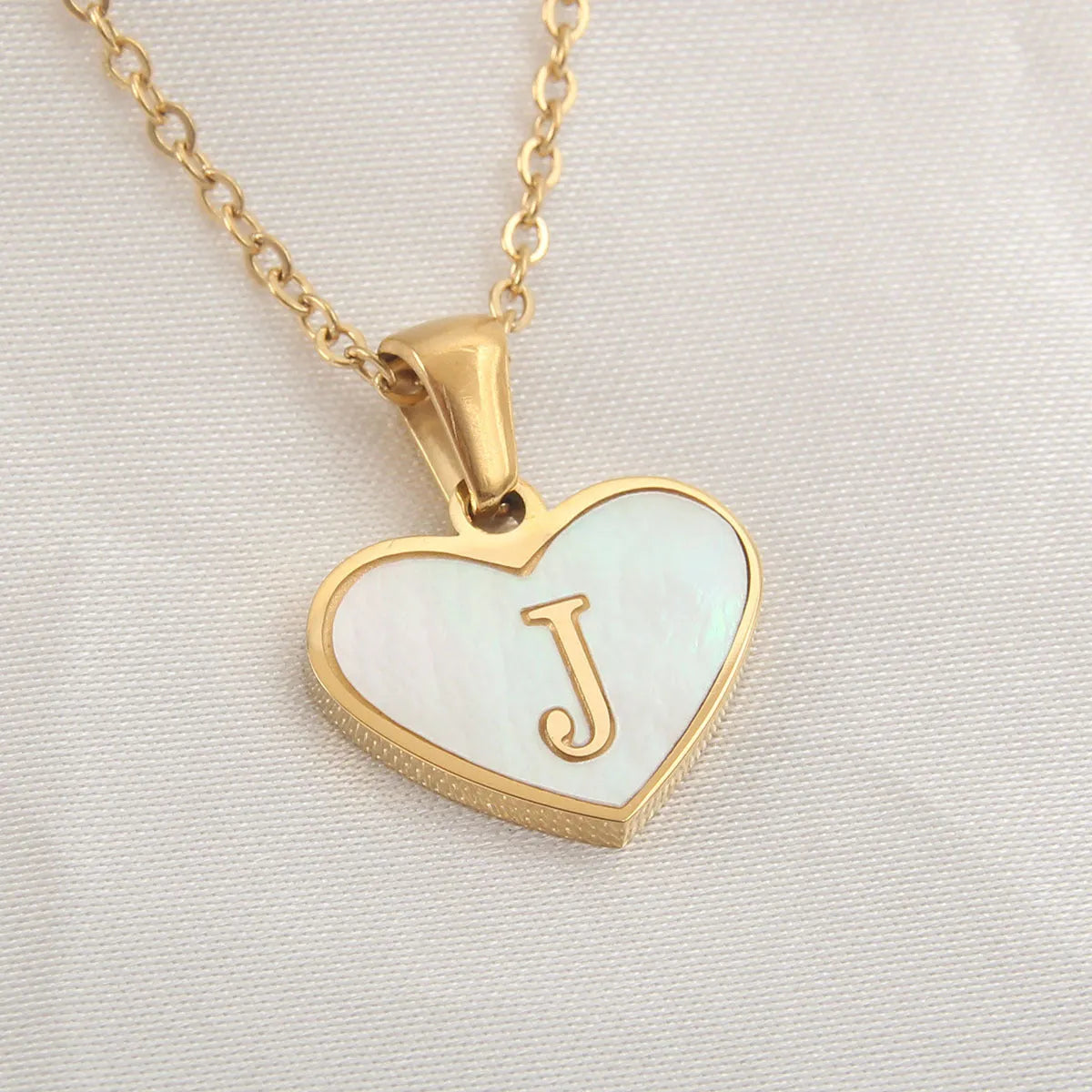 Gold heart necklace with white shell detail and personalised initial letter on adjustable chain