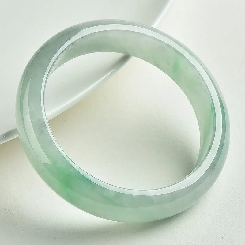Light green jade bracelet showing natural stone texture with sizing chart displaying 53mm to 64mm circumference options