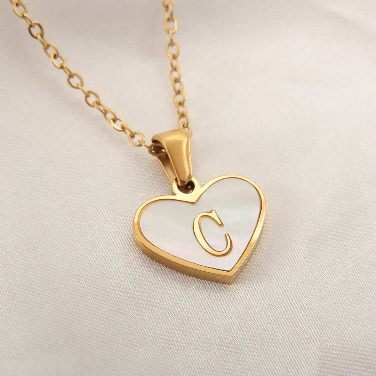 Gold heart necklace with white shell detail and personalised initial letter on adjustable chain