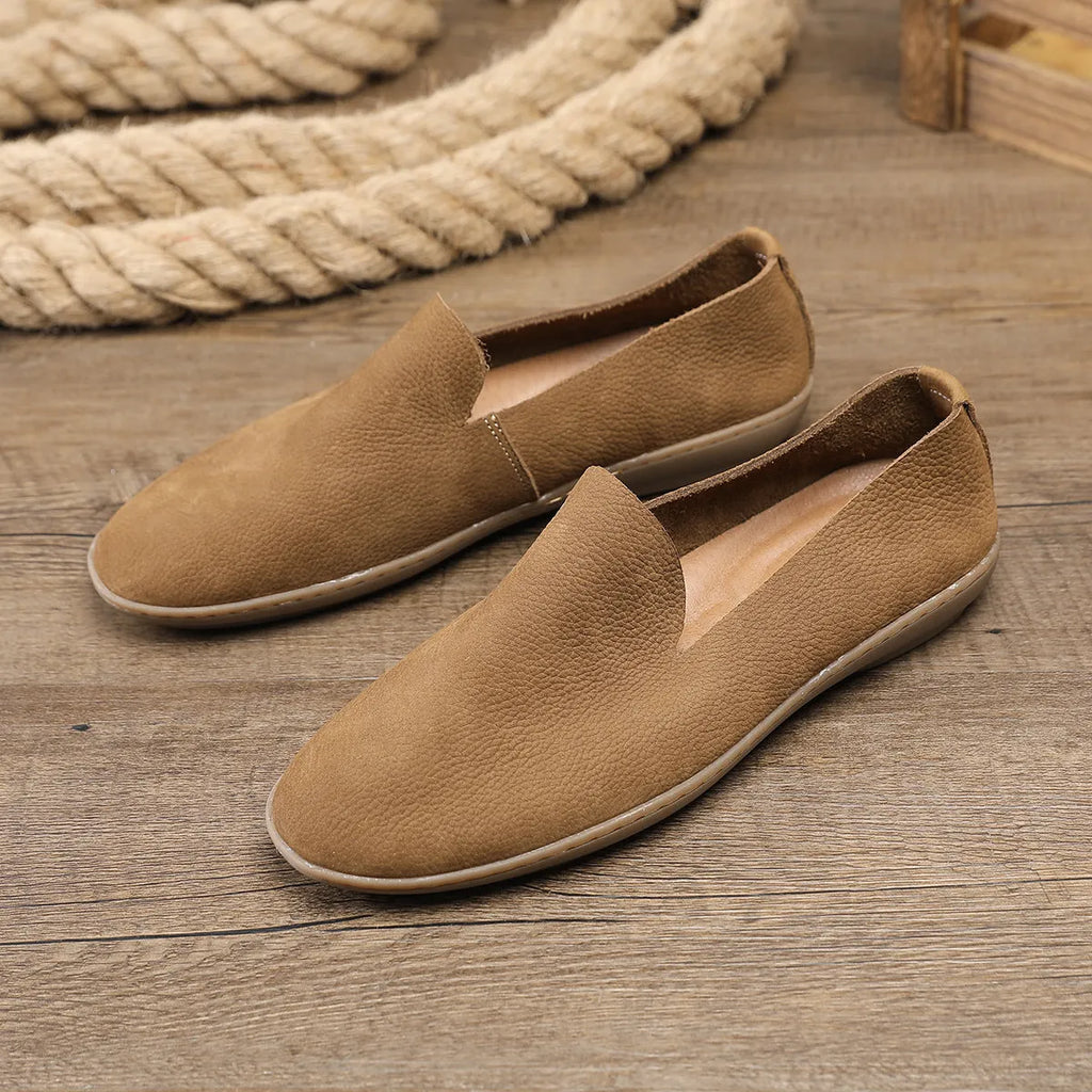 Handmade grey men's low-top leather shoes with a flat wedge rubber sole on a plain background.