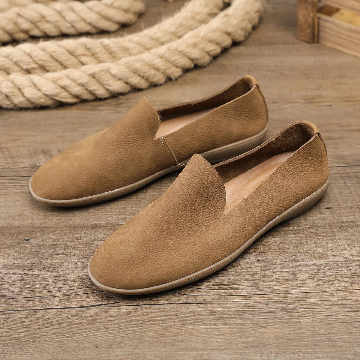 Handmade grey men's low-top leather shoes with a flat wedge rubber sole on a plain background.