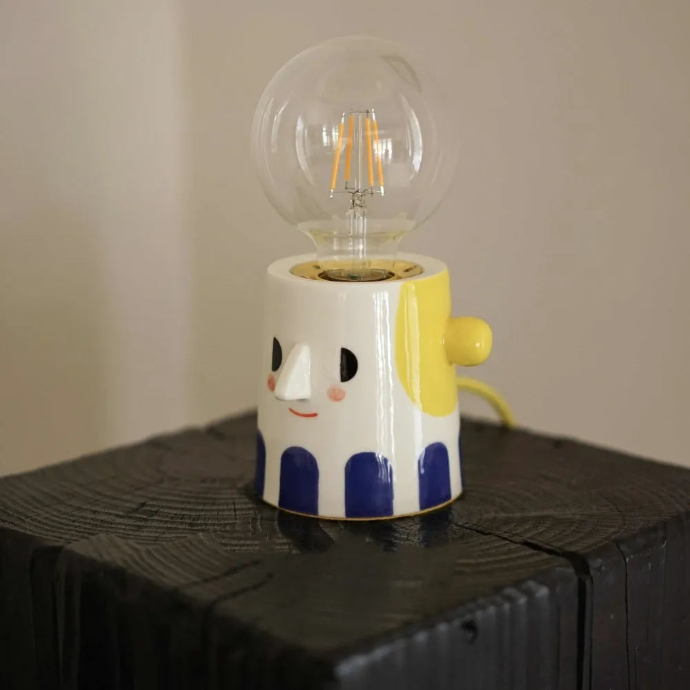 Handmade ceramic table lamp with a spherical ball headlight design on a bedside table.