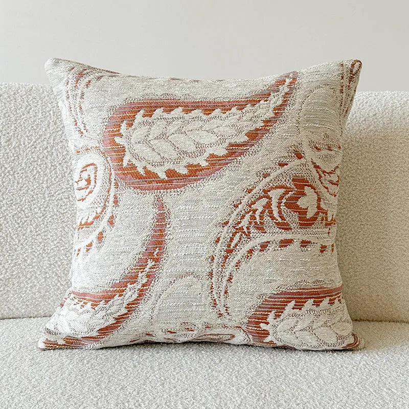 American-style jacquard cushion cover with paisley and flower pattern in amber colours on a sofa.