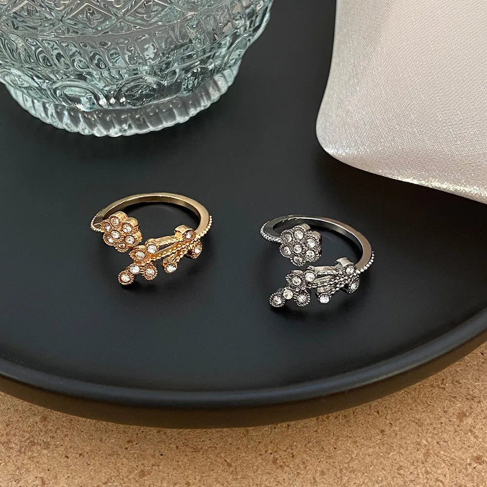 Women's open ring with diamond flower and leaf pattern in copper, shown in gold and white colour options.