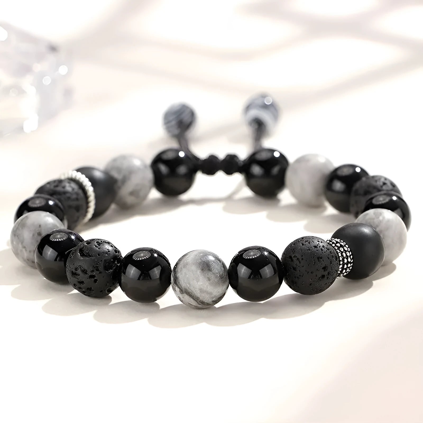 Black agate map stone and volcanic rock bracelet in diamond shape on a wrist.