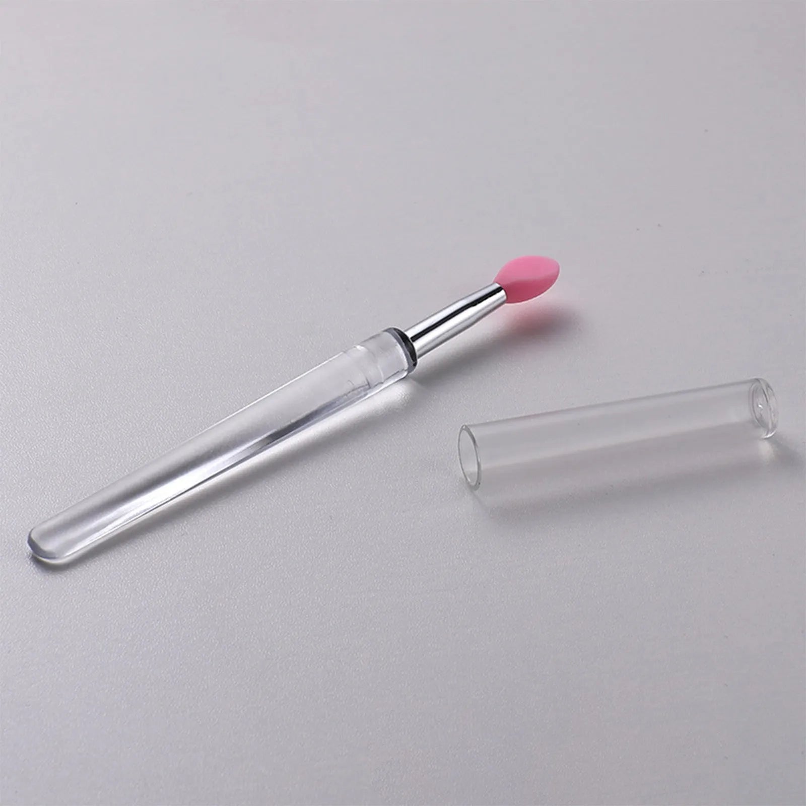 Set of eight colourful reusable silicone lip brushes with hygienic protective caps laid out.