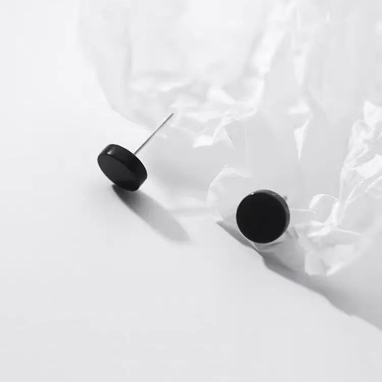 A pair of S999 sterling silver round flat stud earrings on a plain background, showing silver and black colour options.