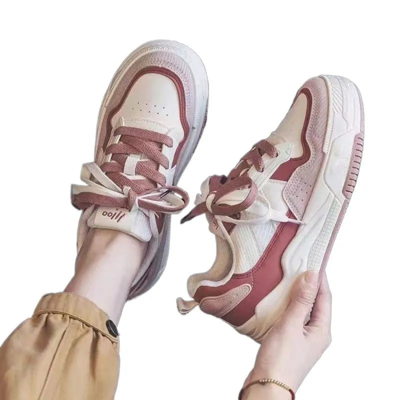 Pink and beige low-top sneakers with a rubber sole and imitation leather upper.