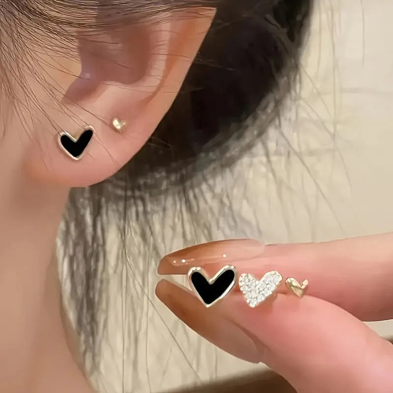 Three pairs of heart-shaped earrings with electroplated alloy construction in gold, black, pink and black-white colours