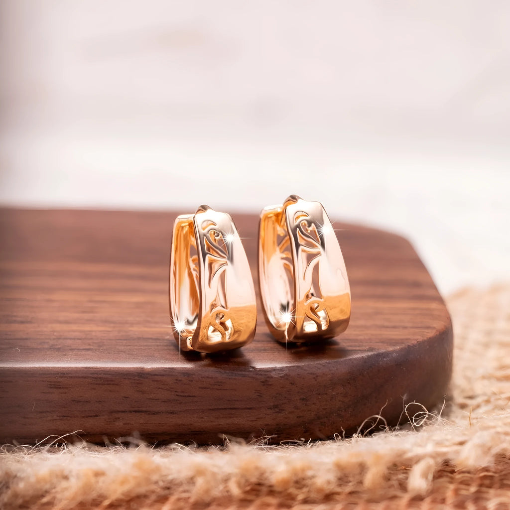 Rose gold hollow carved U-shaped copper earrings on light background