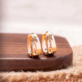 Rose gold hollow carved U-shaped copper earrings on light background