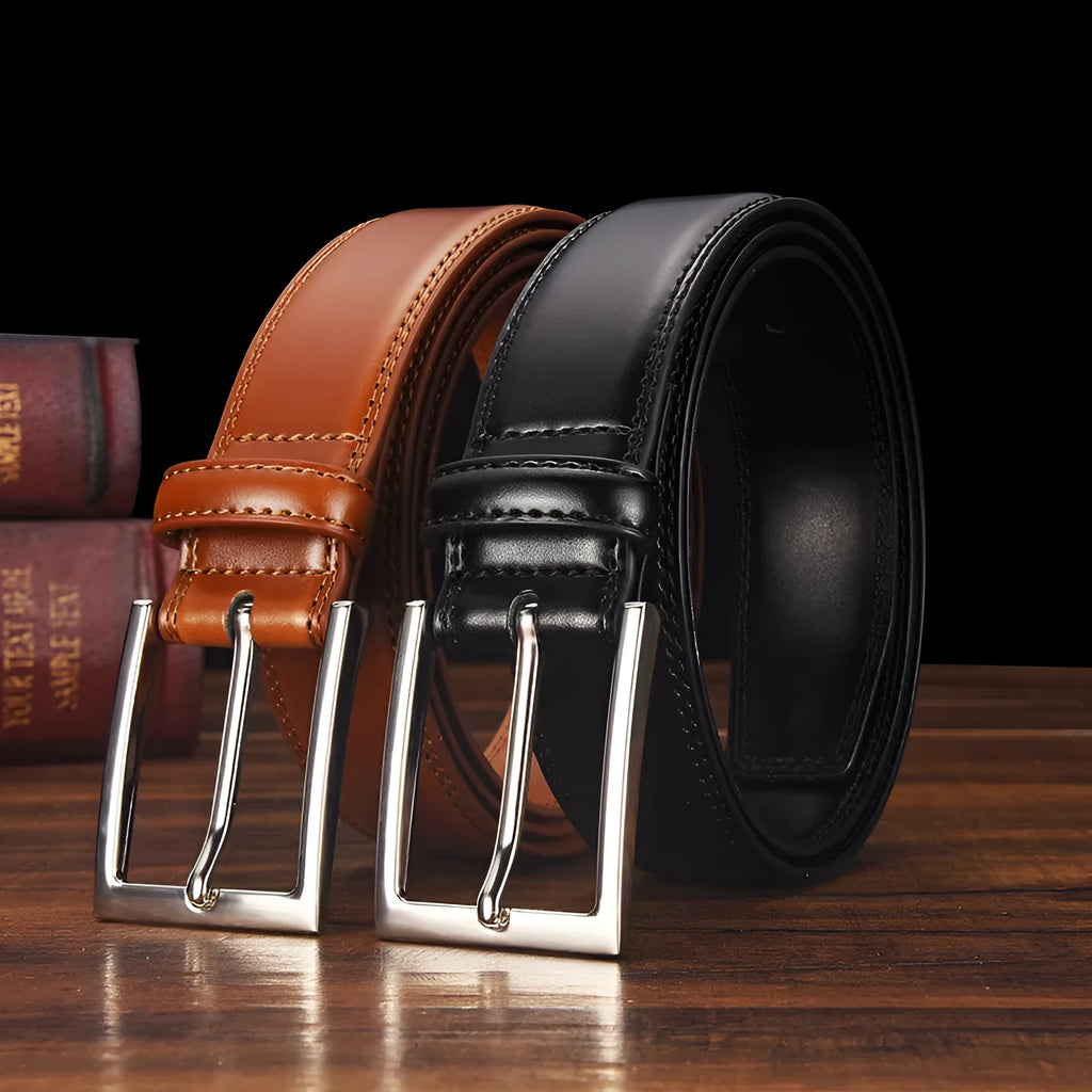 Men's black genuine leather belt with a silver alloy pin buckle on a flat surface