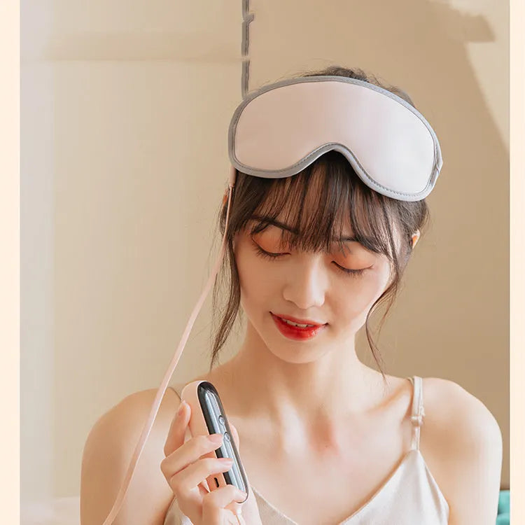 Green portable eye SPA massage goggles with USB cable on a grey background.