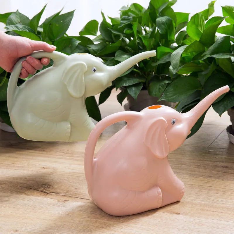 Pink baby elephant-shaped watering can with a long nozzle and bottle-shaped handle on a table.