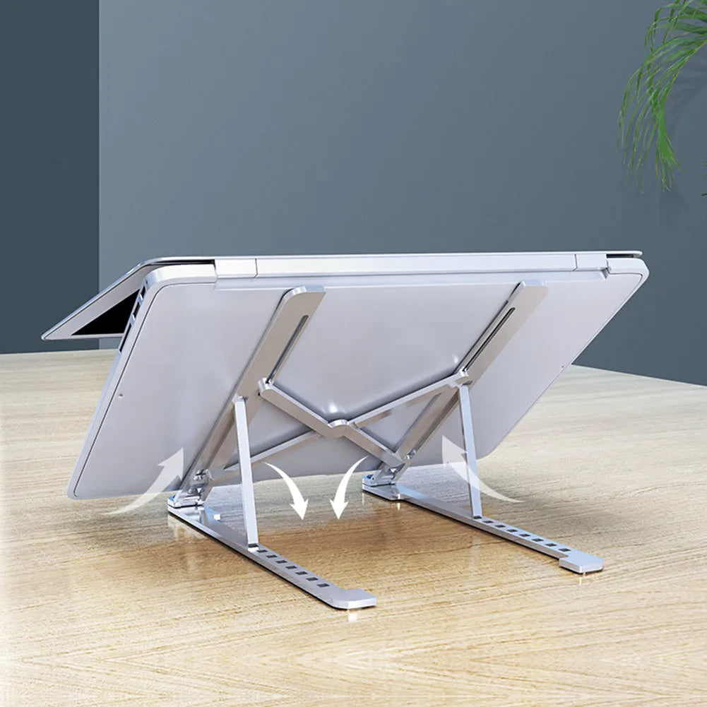 Deep grey portable aluminium laptop stand, folded flat next to an open laptop showing its adjustable height.