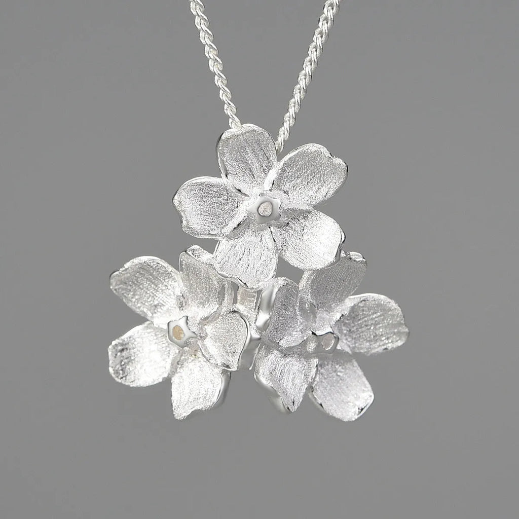 Silver open mouth Myosotis Sylvatica flower pendant with electroplated finish on a dark background.