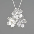 Silver open mouth Myosotis Sylvatica flower pendant with electroplated finish on a dark background.