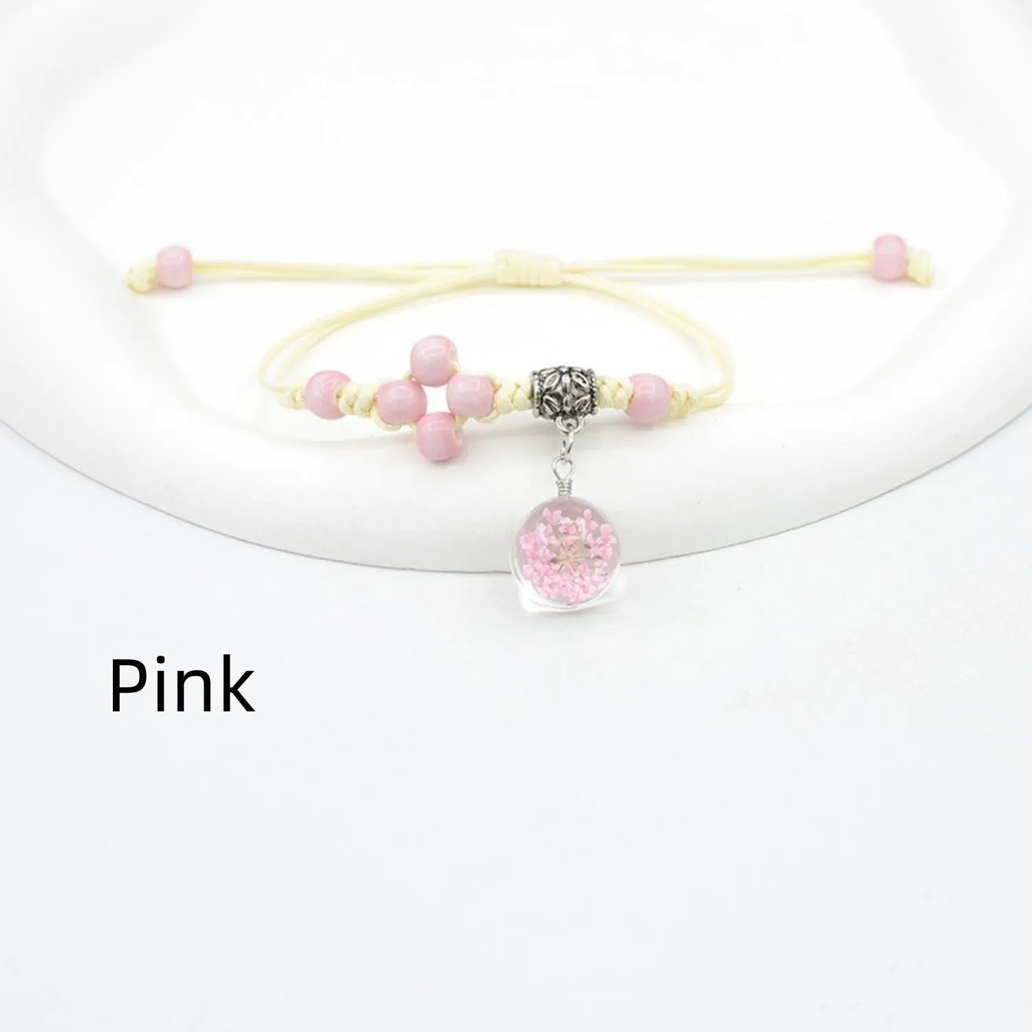 Glass bracelet with large colourful beads containing real dried flowers, on a white background.