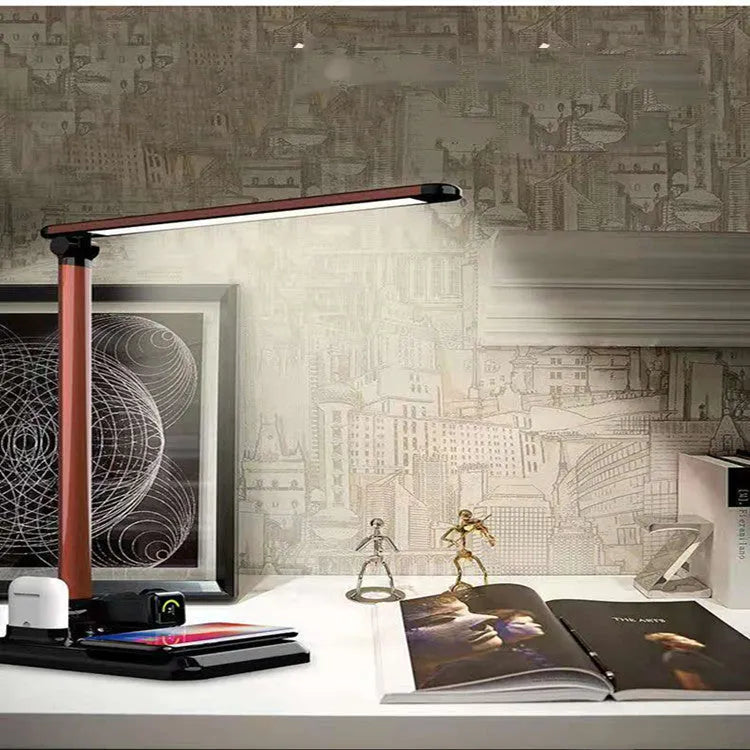 Black and white 4-in-1 LED desk lamp on a desk, showing wireless charging area and USB-C port.