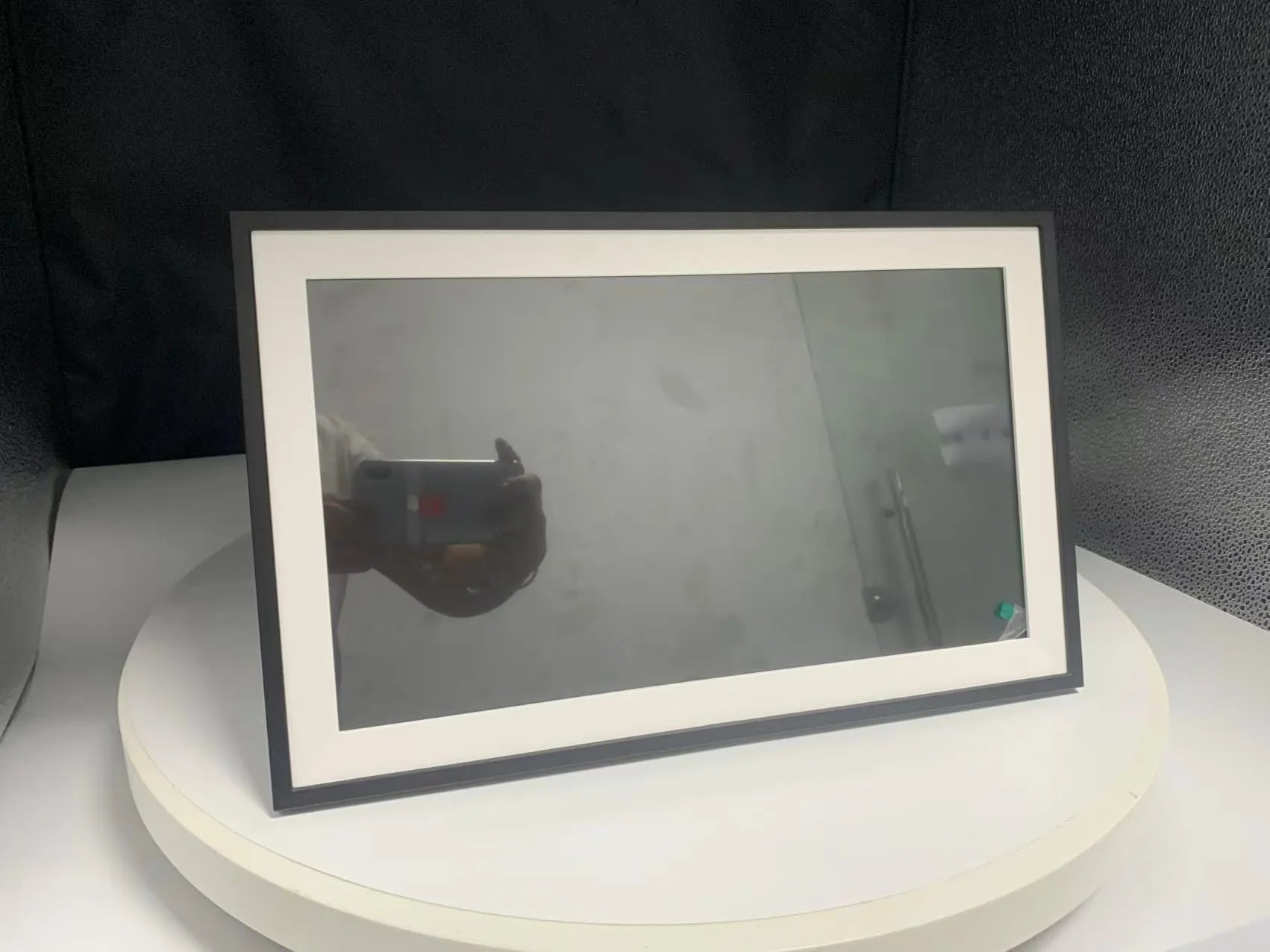 White smart digital photo frame with 15.6 inch screen on a table, showing family photos.