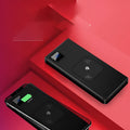 Black portable power bank with LCD display showing battery percentage, next to a smartphone for scale.