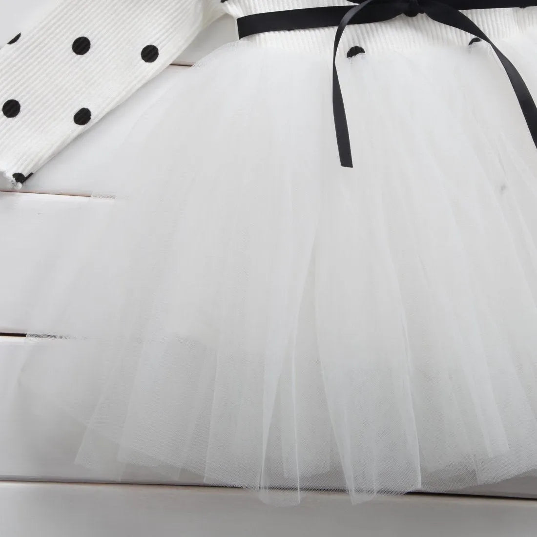 Baby girl wearing a long sleeve lace and tutu dress in pink, suitable for a birthday party.
