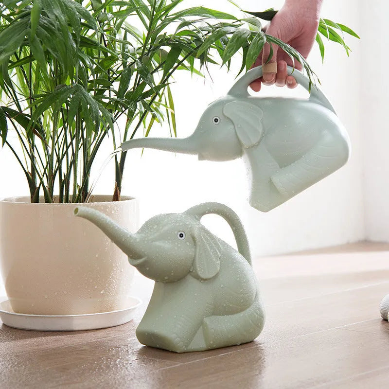 Pink baby elephant-shaped watering can with a long nozzle and bottle-shaped handle on a table.