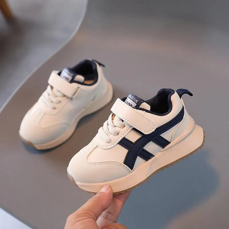 Children's white synthetic leather sneaker with Velcro strap on a neutral background.