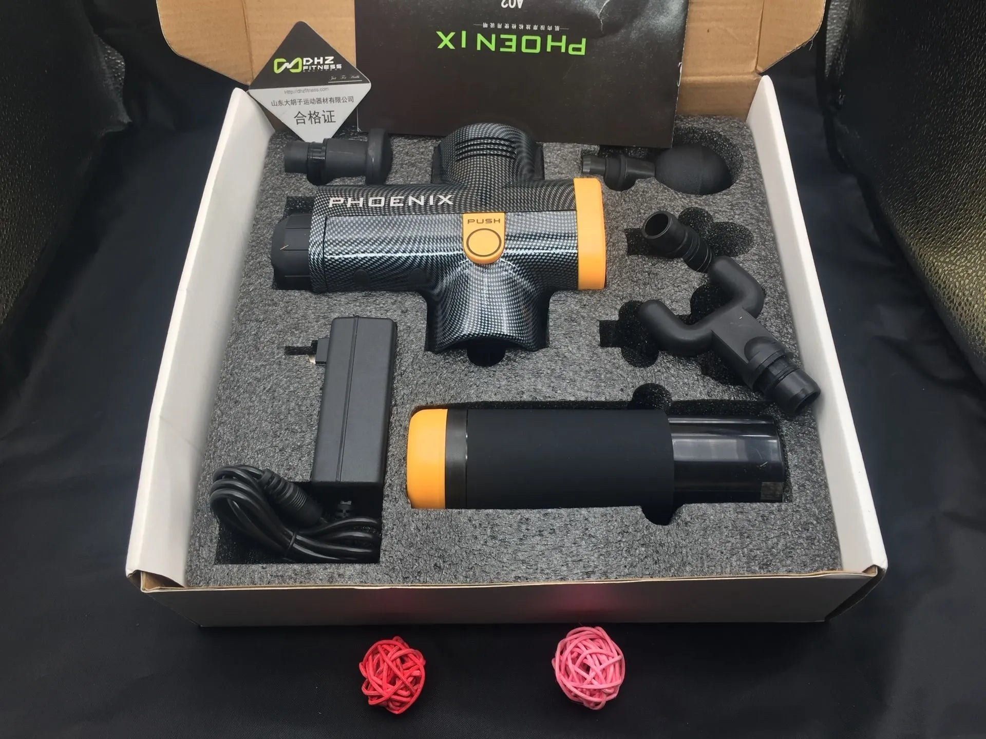 Black and silver deep tissue massage gun with four interchangeable heads on a grey background