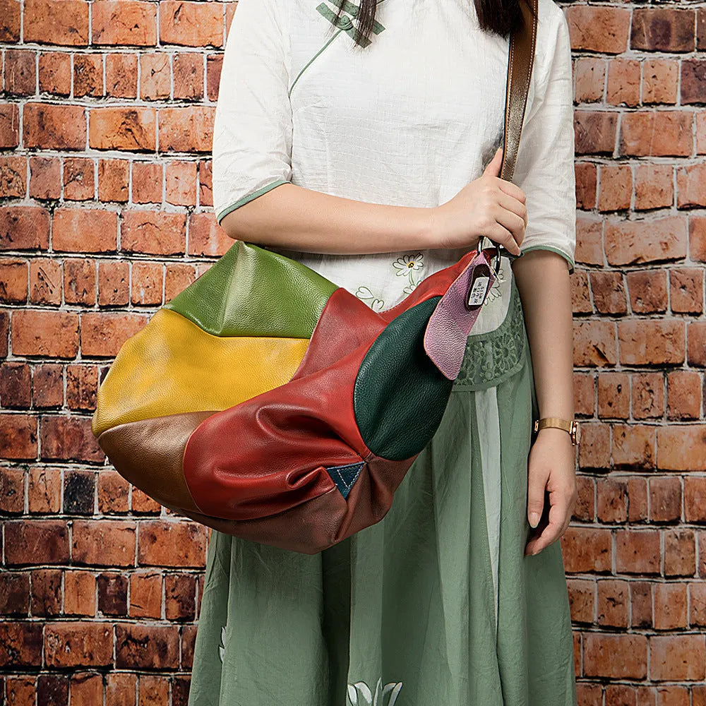 Brown cowhide leather travel bag with stitching detail, shown with a laptop and worn crossbody.
