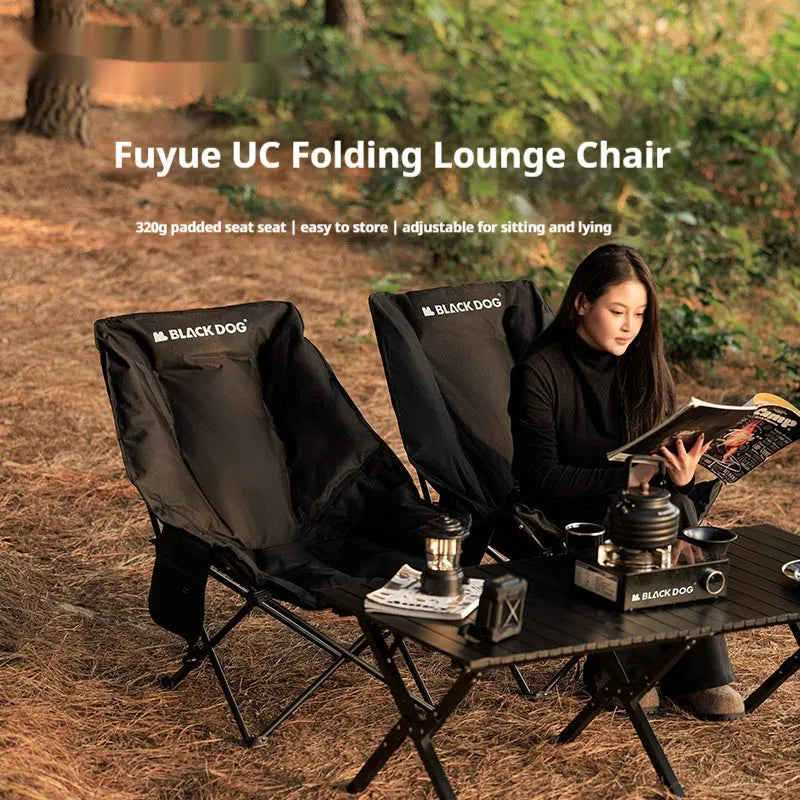 Night Black portable folding moon chair in use outdoors, showing its reclined design and carry handle.