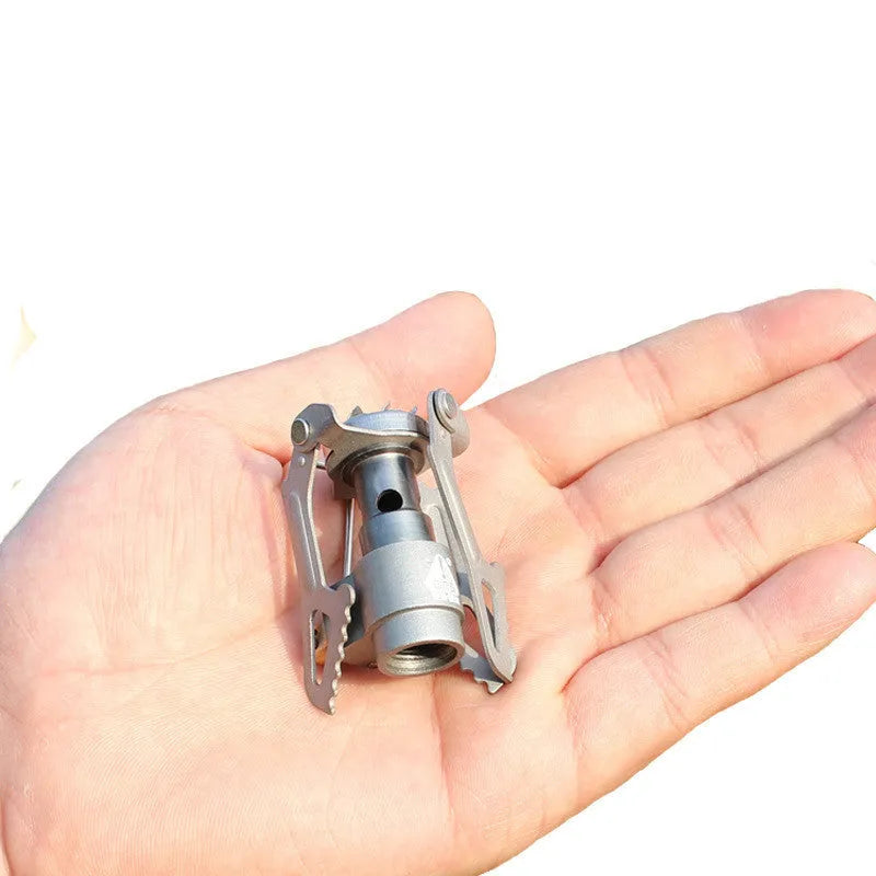 A portable single-burner propane camping stove with a one-piece metal furnace, shown outdoors.