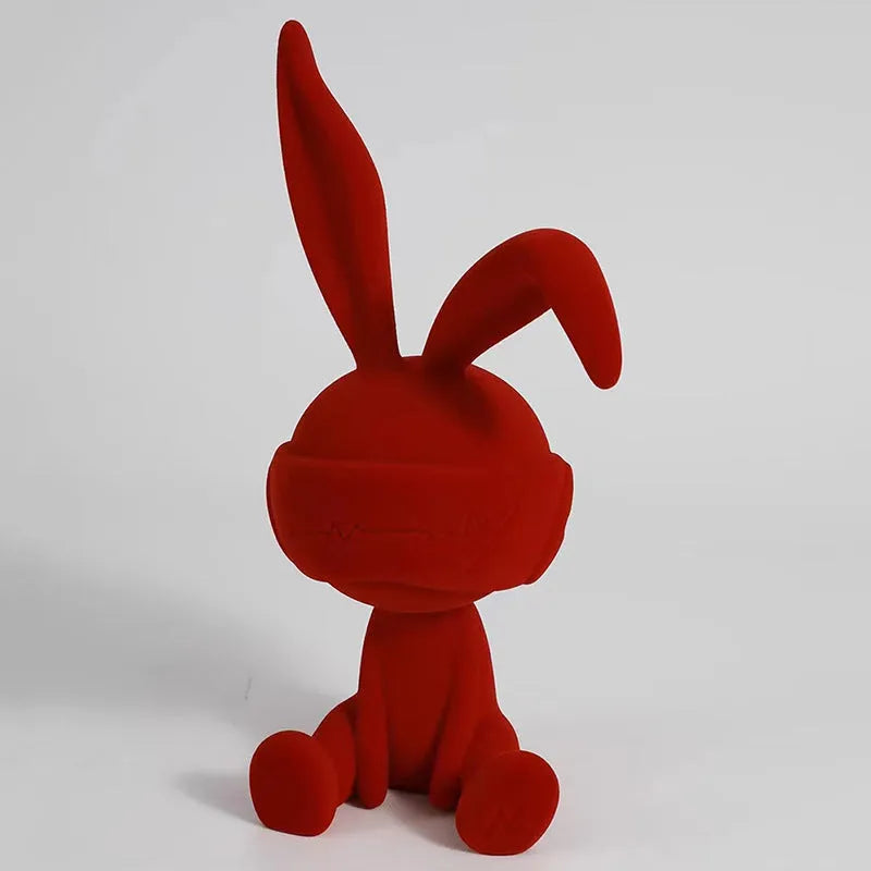 Green resin blindfold rabbit table ornament on a wooden surface.