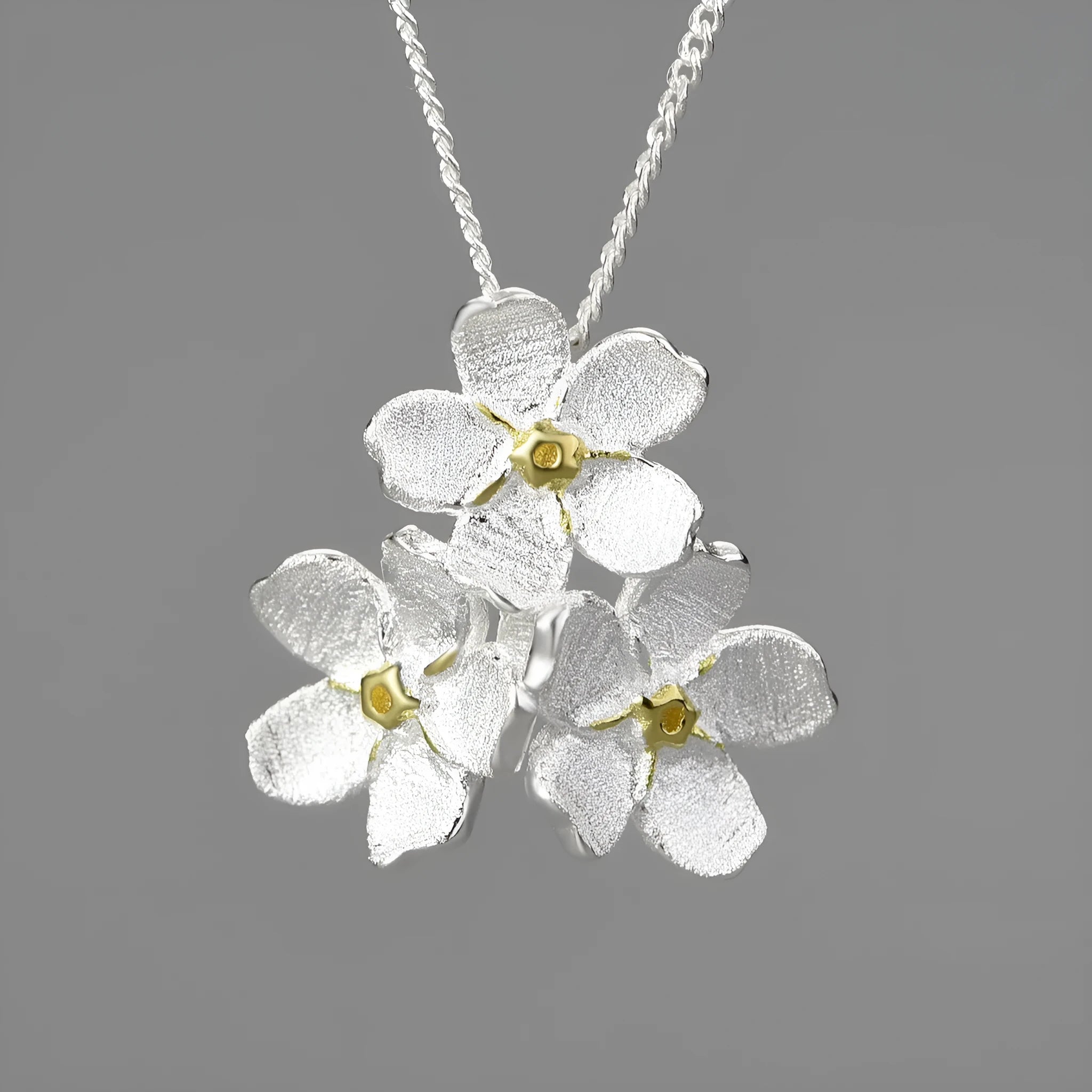 Silver open mouth Myosotis Sylvatica flower pendant with electroplated finish on a dark background.