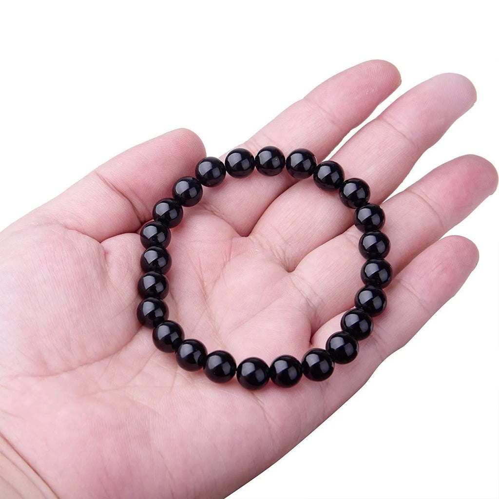 Close-up of a women's geometric bracelet with black agate beads on a black elastic cord.
