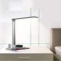 Black and white 4-in-1 LED desk lamp on a desk, showing wireless charging area and USB-C port.